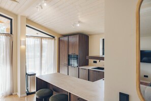 Una cocina moderna con armarios de madera, horno empotrado y una zona de bar con taburetes.