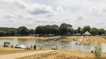 Een park aan het meer met een zandstrand, een glijbaan en een kiosk.