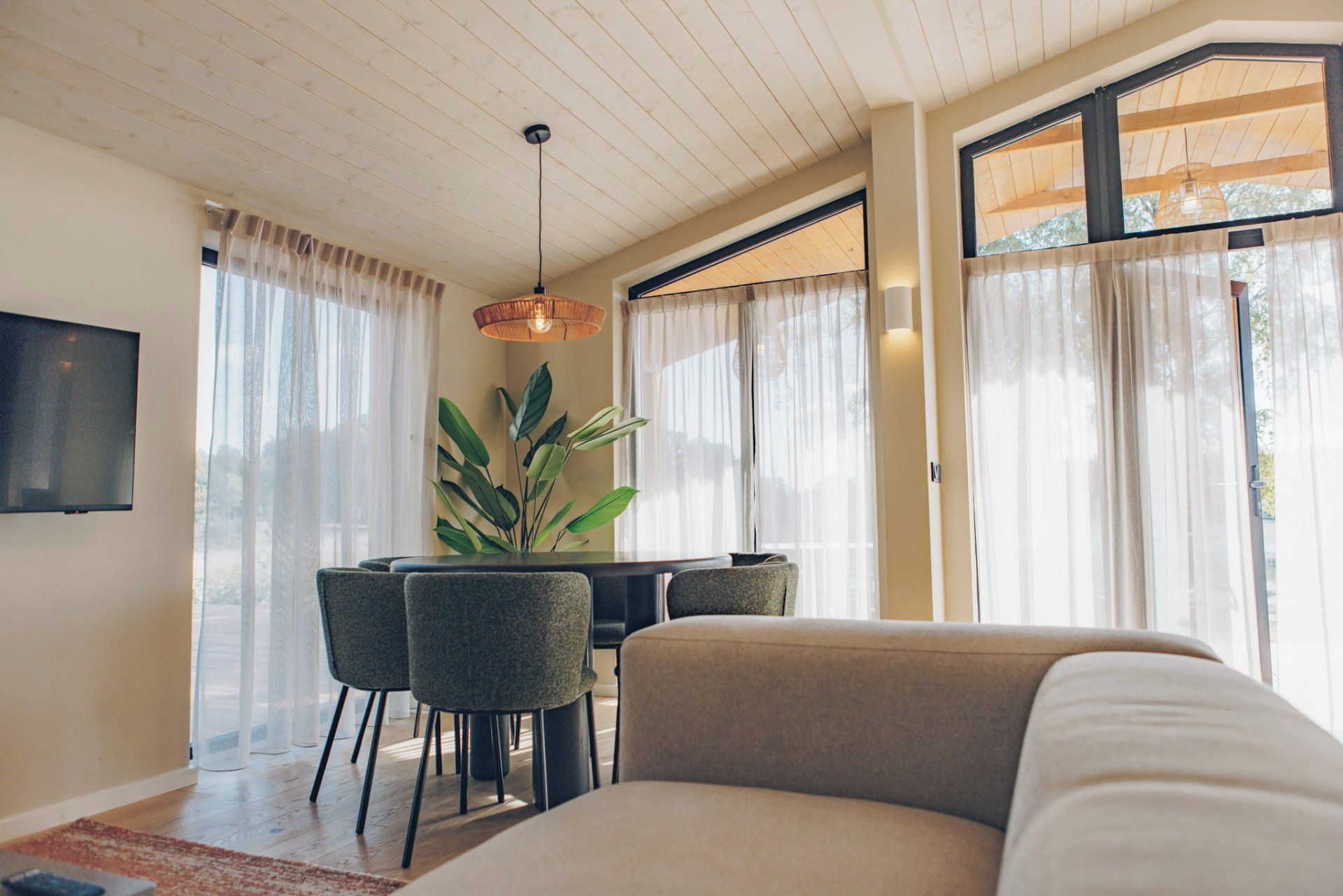 A modern living room with a sofa, dining table, chairs, and a TV.