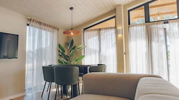 A modern living room with a sofa, dining table, chairs, and a TV.