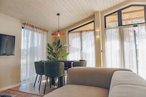 A modern living room with a sofa, dining table, chairs, and a TV.