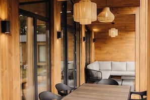 A wooden interior with a dining table, chairs, and a sofa.