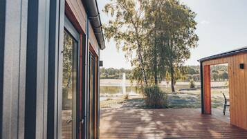Une terrasse en bois offrant une vue sur un lac et des arbres.