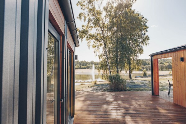 A wooden deck with a view of a lake and trees.
