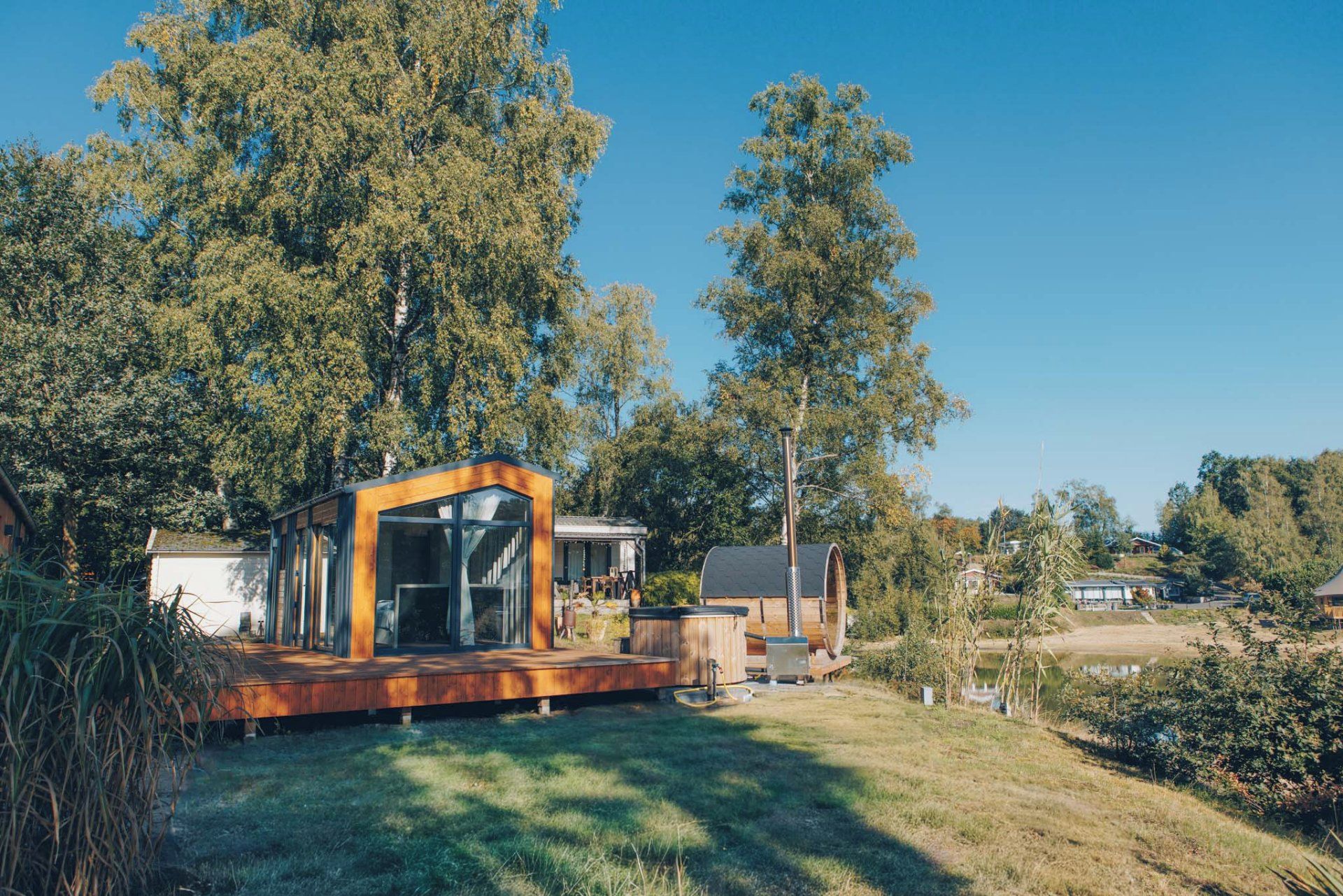 Een moderne buitenstructuur met een glazen omheining, een houten terras en een schoorsteen.