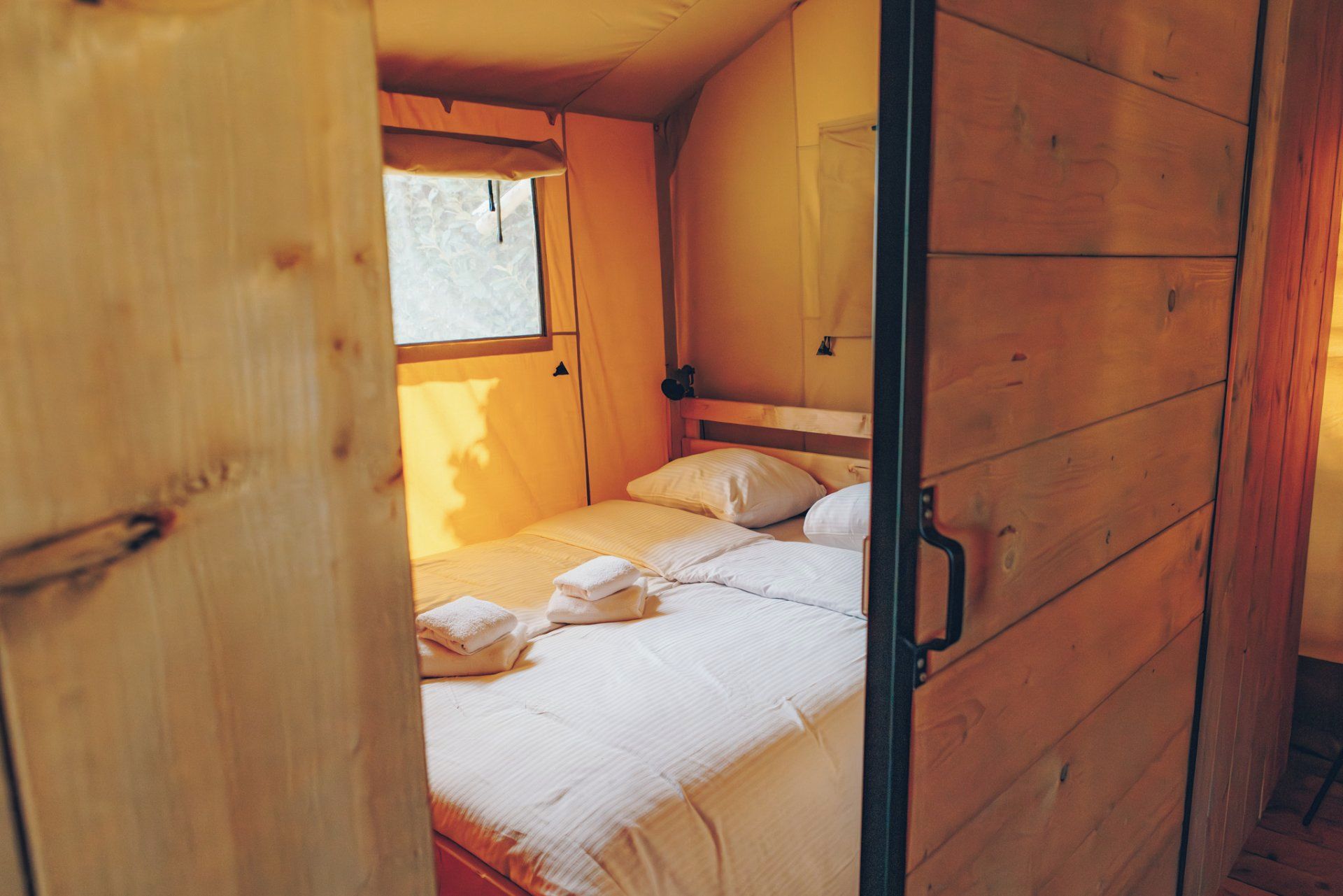 A wooden interior with a bunk bed, a window, and a door.
