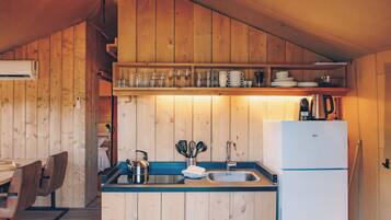 A compact kitchen with wooden cabinets, a sink, a kettle, and a white refrigerator.
