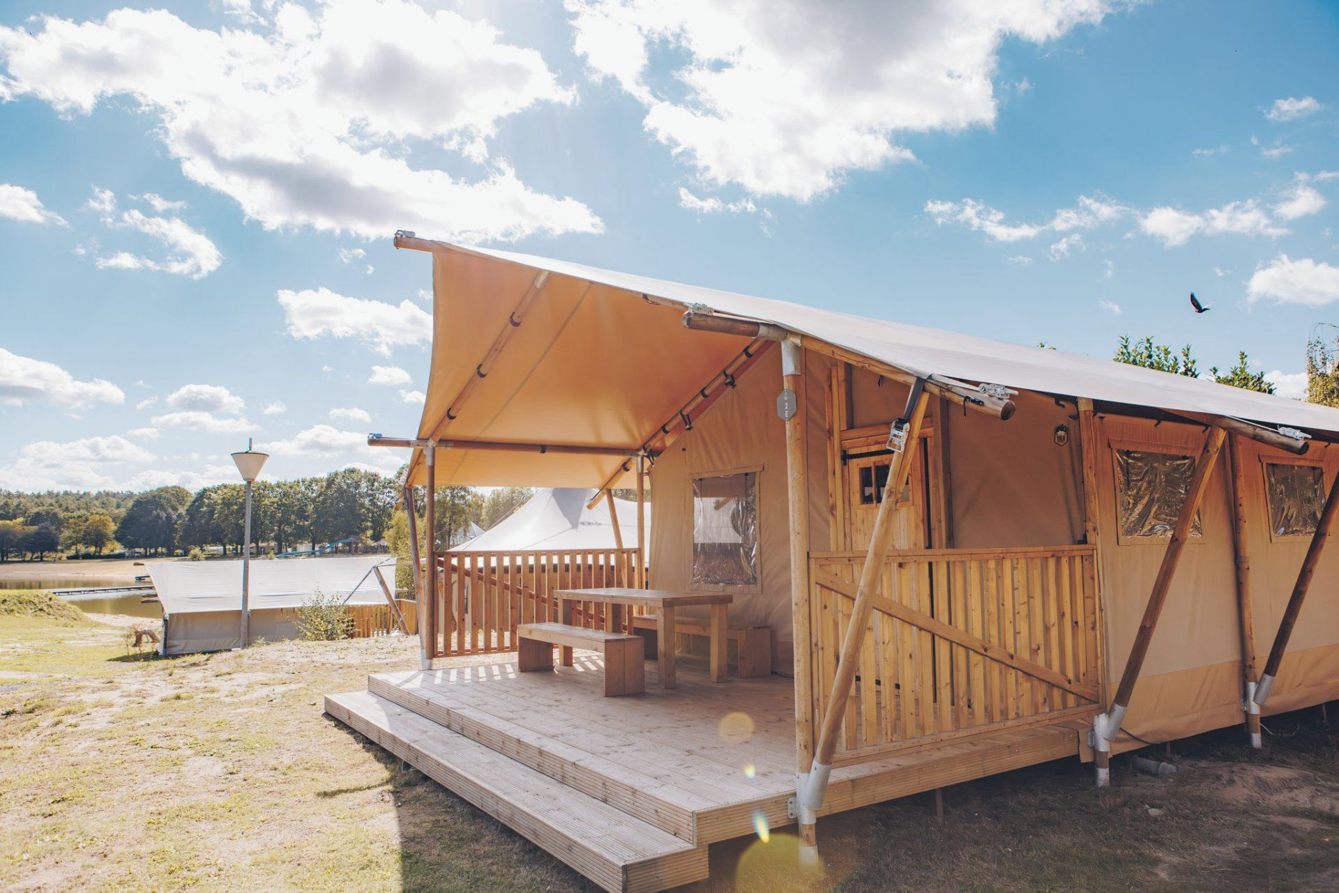Ett tält av trä med en inglasad veranda och ett bord, placerat mot en klar himmel.
