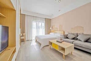 Una habitación de hotel con una cama, un sofá, un televisor y un escritorio.