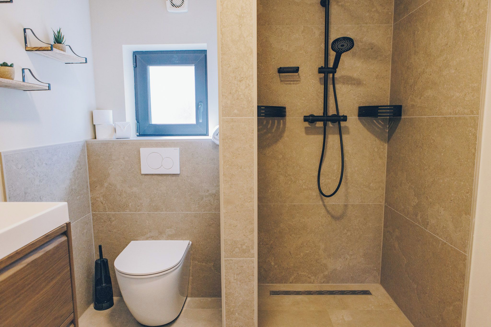 Ein Badezimmer mit Toilette, Dusche und Fenster.