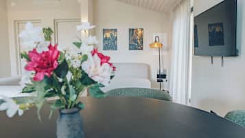 Een moderne hotelkamer met een bed, een tafeltje met bloemen, een lamp en kunst aan de muur.