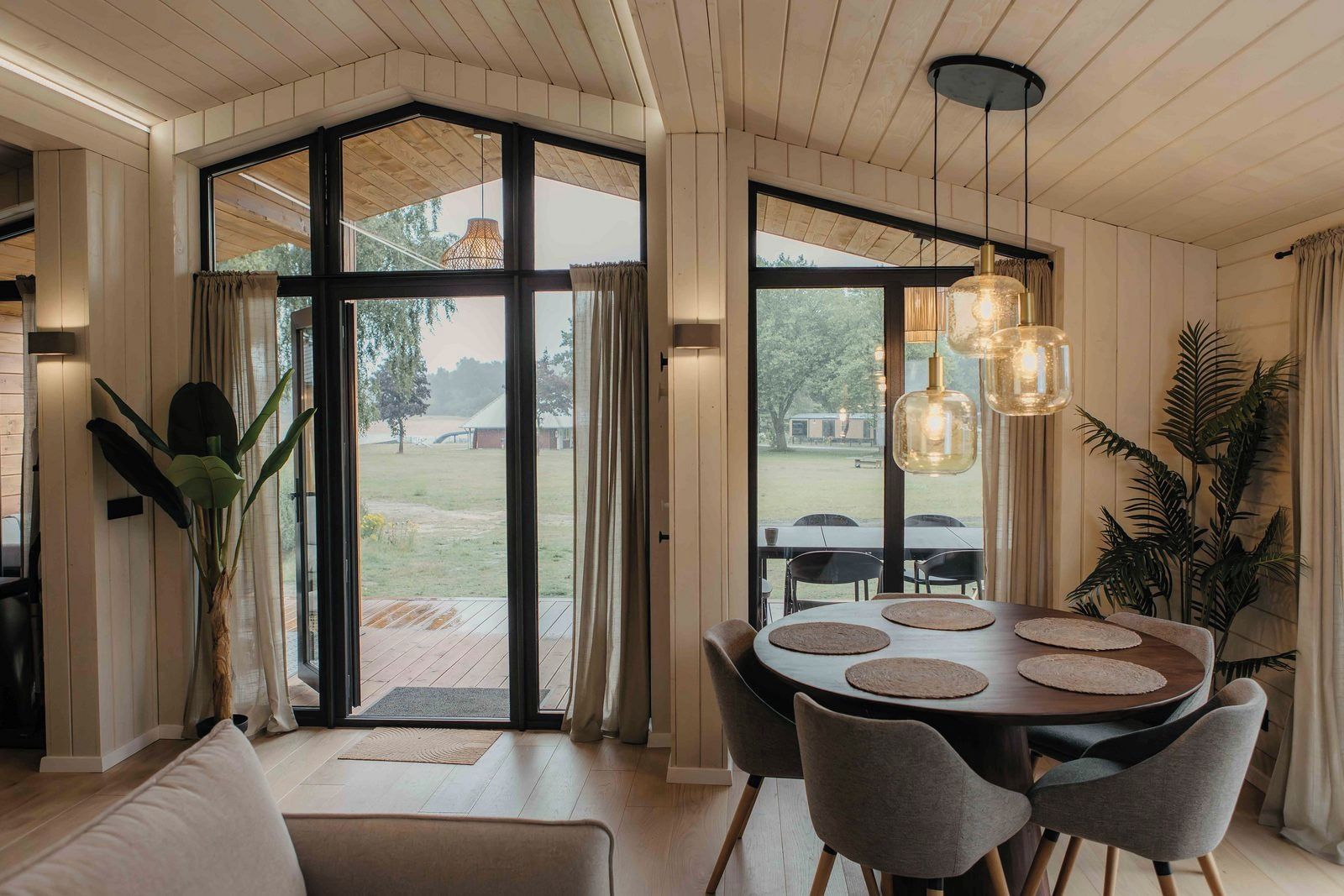 Un espace repas comprenant une table ronde, des chaises et une vue sur l’extérieur grâce à de grandes fenêtres.