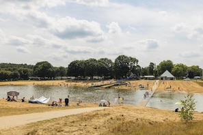 A lakeside park with a sandy beach, a water slide, and a pavilion.