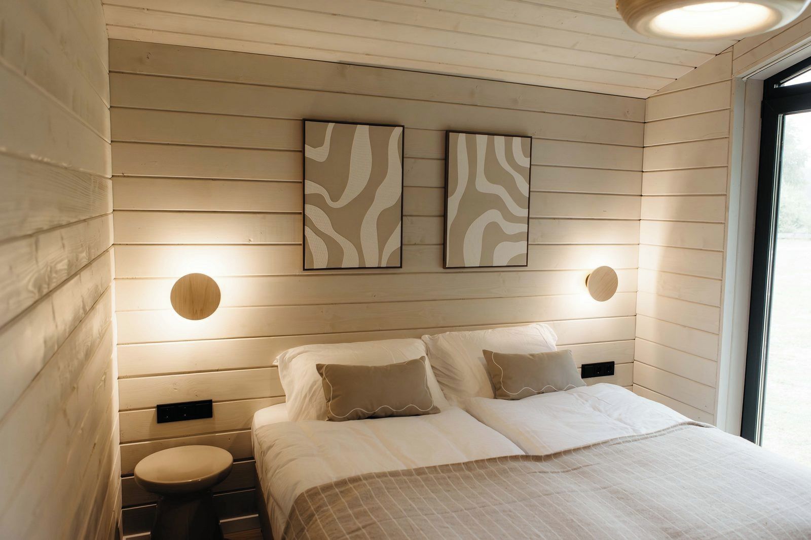 Une chambre à coucher avec un lit, deux lampes fixées au mur et une fenêtre.
