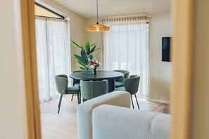 A dining area with a round table, six chairs, and a potted plant with flowers.