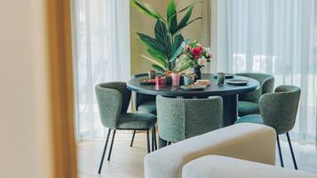 Een ronde eettafel met zes stoelen, een potplant en een vaas met bloemen.
