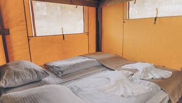 Uma cama de solteiro num quarto com paredes de madeira e uma janela.