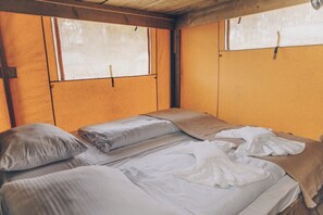 A single bed in a room with wooden walls and a window.