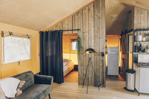 Una habitación acogedora con cama, sofá, kitchenette y pared de madera.