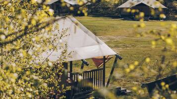 Un terrain de camping avec des tentes et une structure en bois dotée d’un toit.