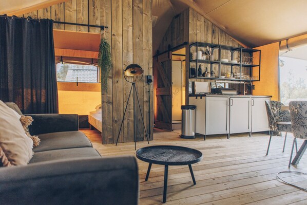 A cozy living area with a sofa, a small round table, and a kitchen area with shelves and a countertop.