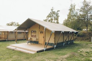 Een eenpersoons tent met een houten terras en een klein zitgedeelte.
