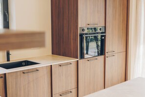 A kitchenette with a sink, cabinets, and a built-in oven.