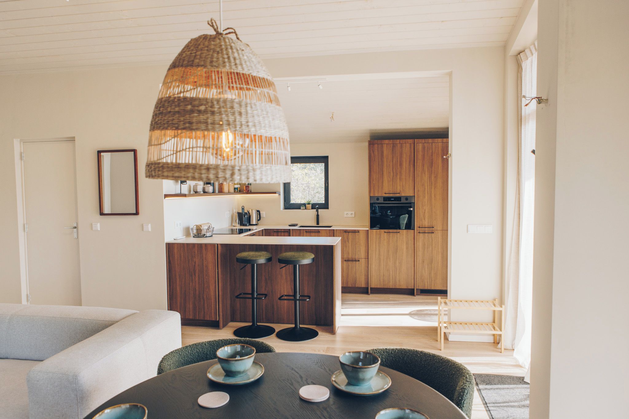 A modern kitchen with wooden cabinets, a central island, and bar stools.
