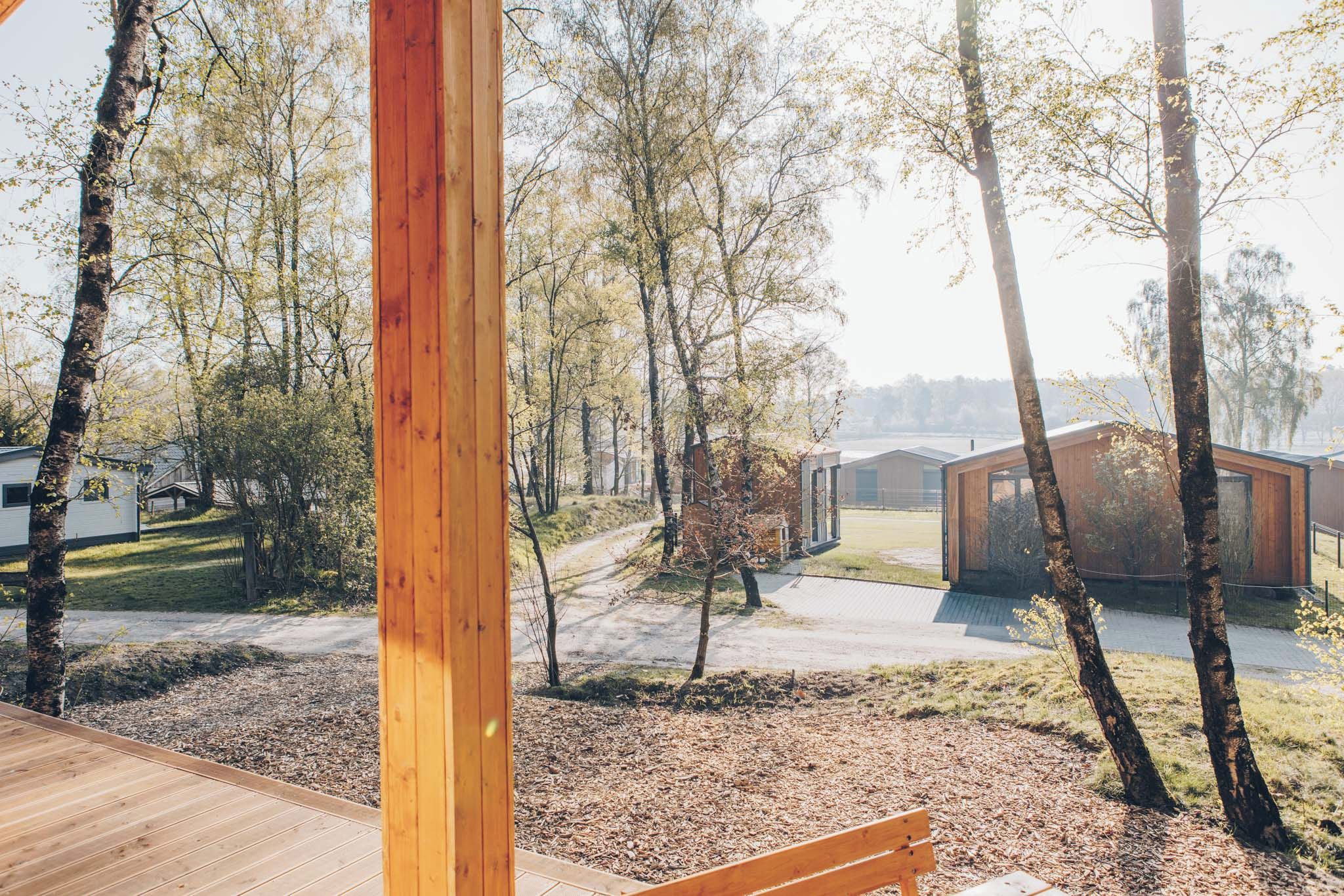 Une terrasse en bois offrant une vue sur une zone boisée et des bâtiments modernes.