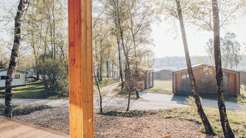 Une terrasse en bois offrant une vue sur une zone boisée et des bâtiments modernes.
