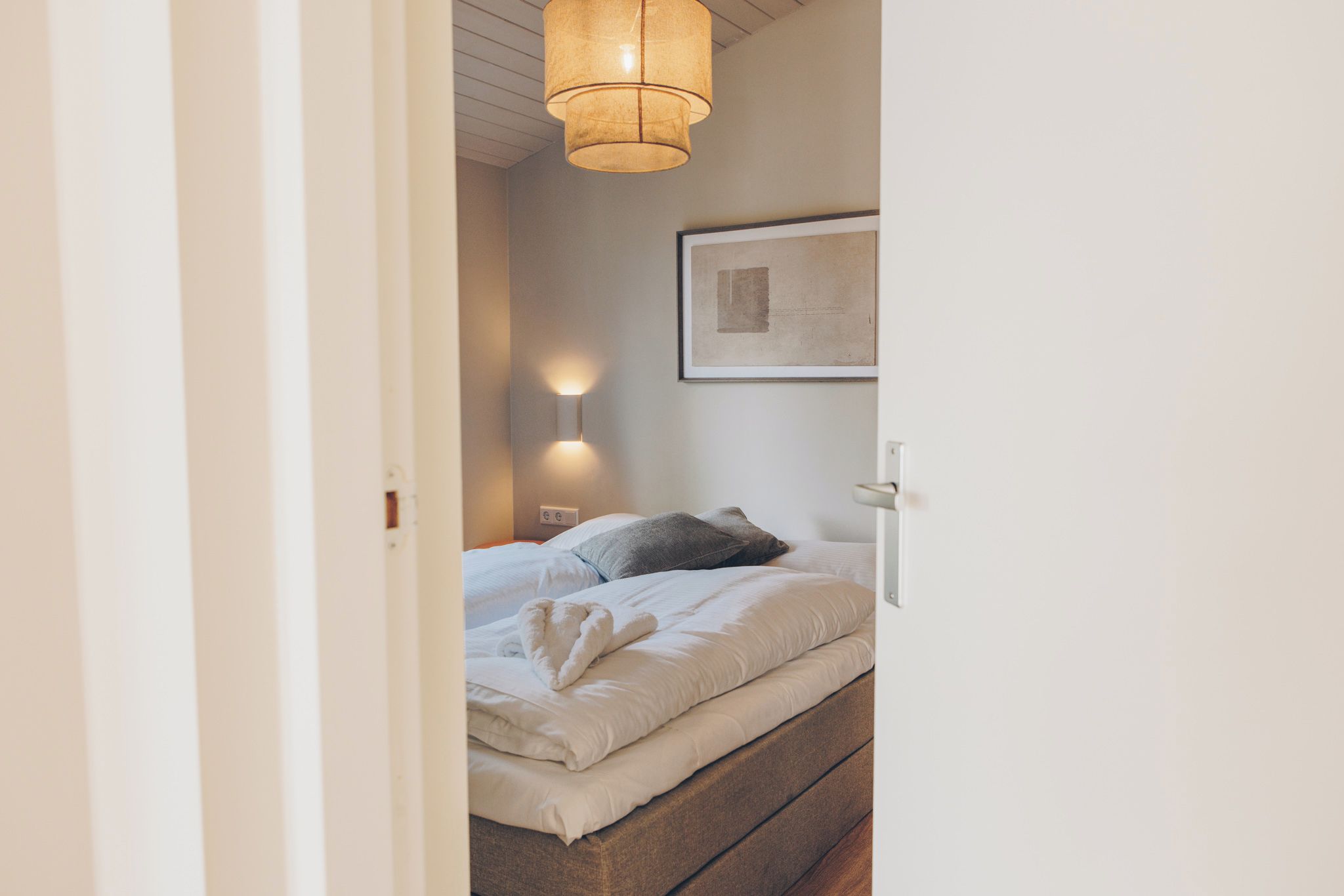 Une chambre à coucher avec un lit, une lampe de chevet et un tableau encadré au mur.