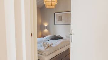 Une chambre à coucher avec un lit, une lampe de chevet et un tableau encadré au mur.