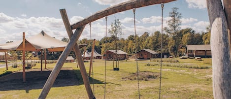 Un parque infantil con columpios y una zona de estar cubierta.