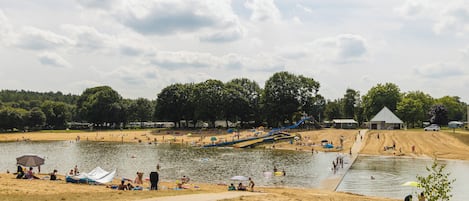 A lakeside park with sandy areas, a boat ramp, and a small building.