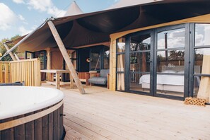 Eine Holzterrasse mit Whirlpool, Esstisch und einer Sitzecke.