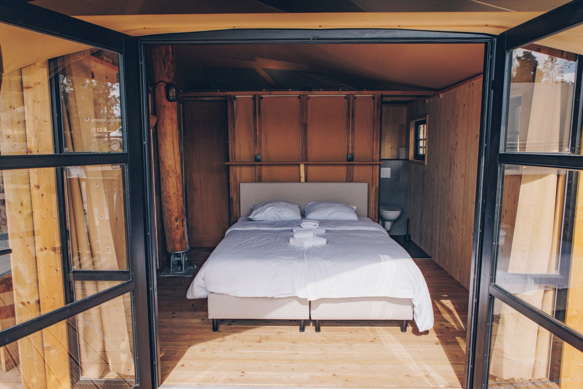 Een bed met hoofdeinde, nachtkastje en raam.