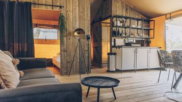 A cozy living area with a sofa, a small round table, and a kitchen area with shelves and a countertop.