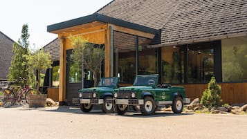 Deux véhicules Defender verts sont stationnés devant un bâtiment doté d’un patio couvert.