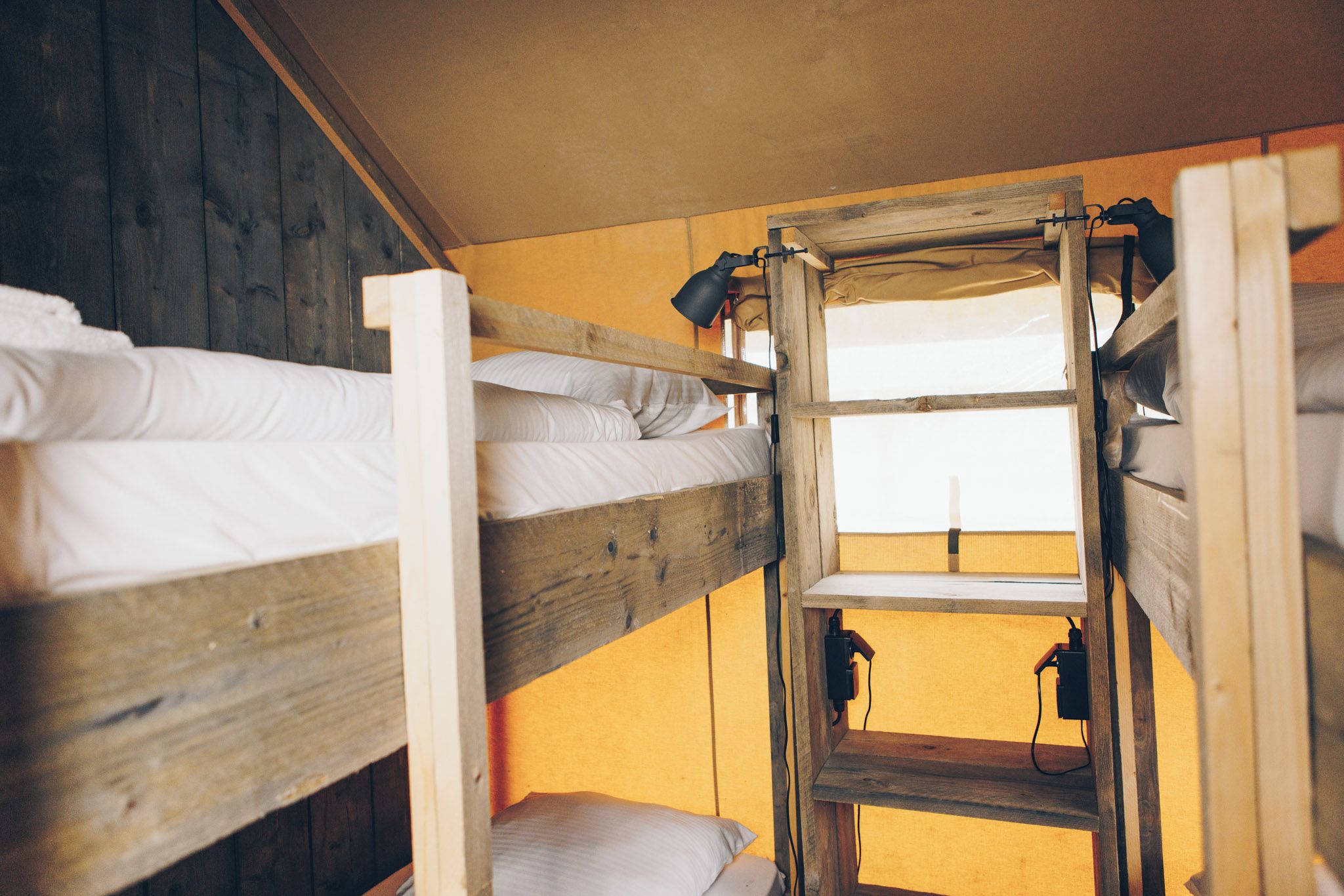 Une chambre avec un lit superposé, des murs en bois et une fenêtre.