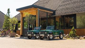 Deux véhicules Defender verts sont stationnés devant un bâtiment doté d’un patio couvert.