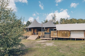 Um camping com duas tendas, decks de madeira e uma área gramada.