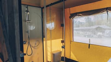 Baño compacto con ducha, inodoro y ventana con vistas a un paisaje nevado.