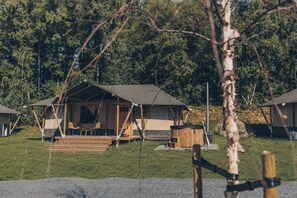 Una cabaña rústica con porche, jacuzzi y chimenea, rodeada por un bosque.