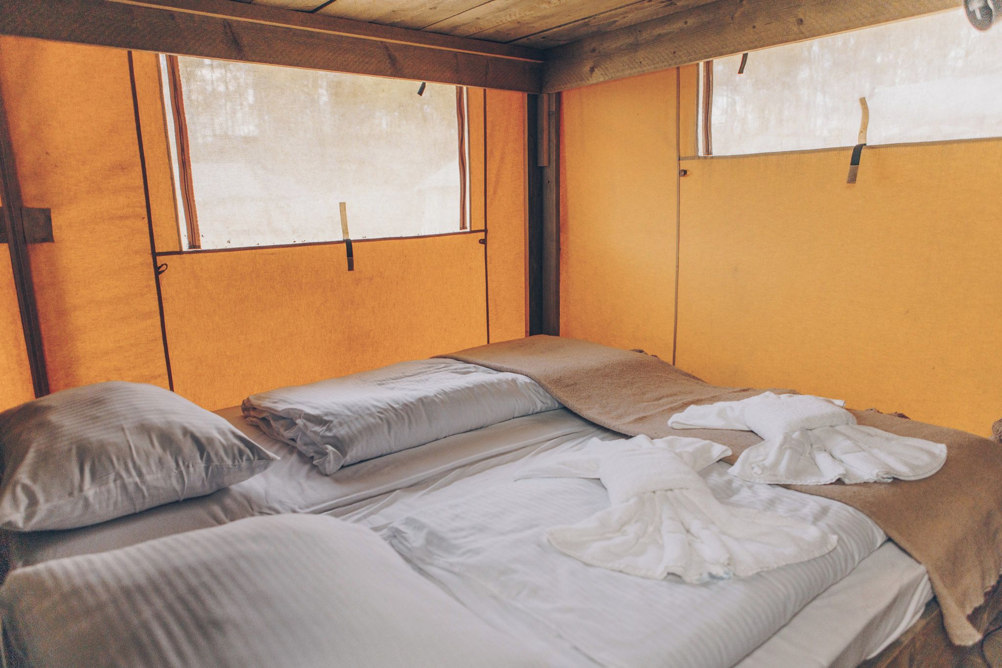 Un lit simple dans une pièce aux murs en bois et dotée d’une fenêtre.