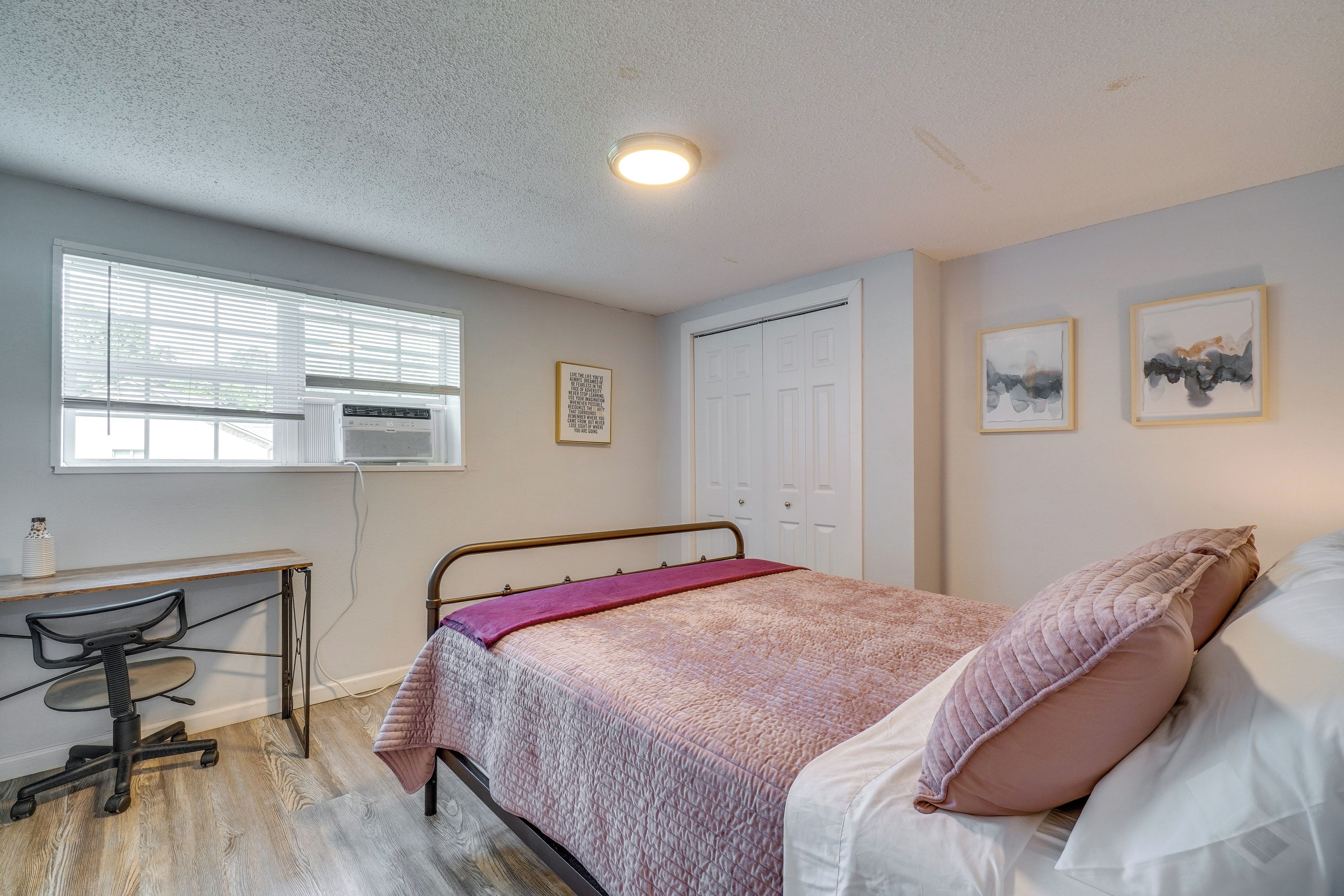 A bedroom with a bed, a desk, and a chair.