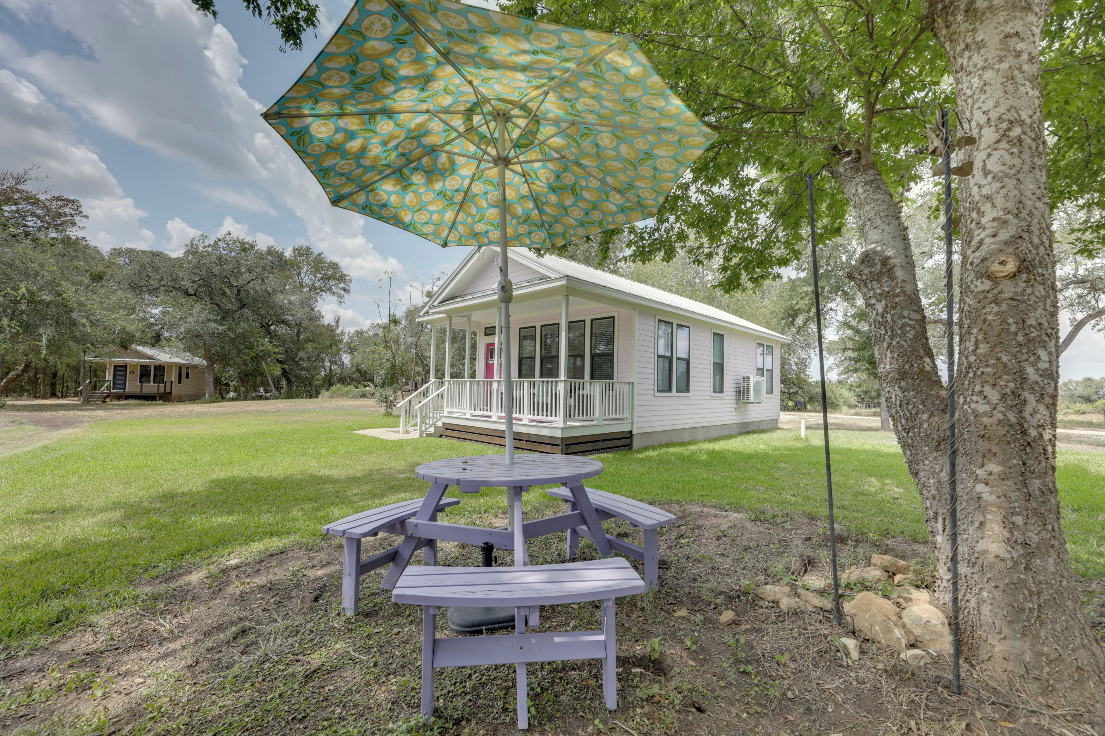 Une maison avec une véranda, une table de pique-nique et un parasol.