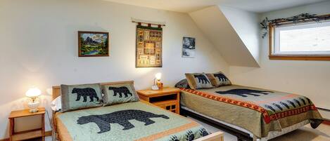 Un dormitorio con dos camas, cada una con colcha temática de osos, una mesita de noche con lámpara y una pared con tres cuadros enmarcados.