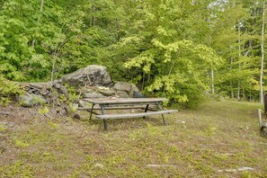 A picnic table in a wooded area with rocks and trees around. - Vermont Cabin Escape | Okemo, Hiking & Fireplace (Cavendish)