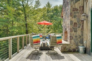 A wooden deck with outdoor furniture and a red umbrella.