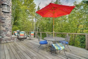 A wooden deck with outdoor furniture, a red umbrella, and a stone wall. - Vermont Cabin Escape | Okemo, Hiking & Fireplace (Cavendish)
